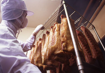 職人が燻製室からベーコンを取り出しているシーン