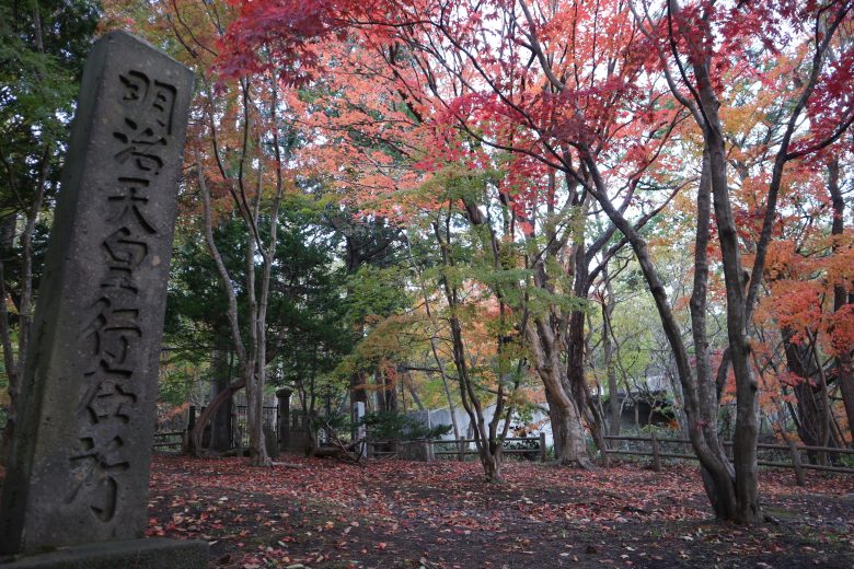 旧島松駅逓所の敷地に立つ「寒地稲作この地に始まる」の碑と、色づいた木々