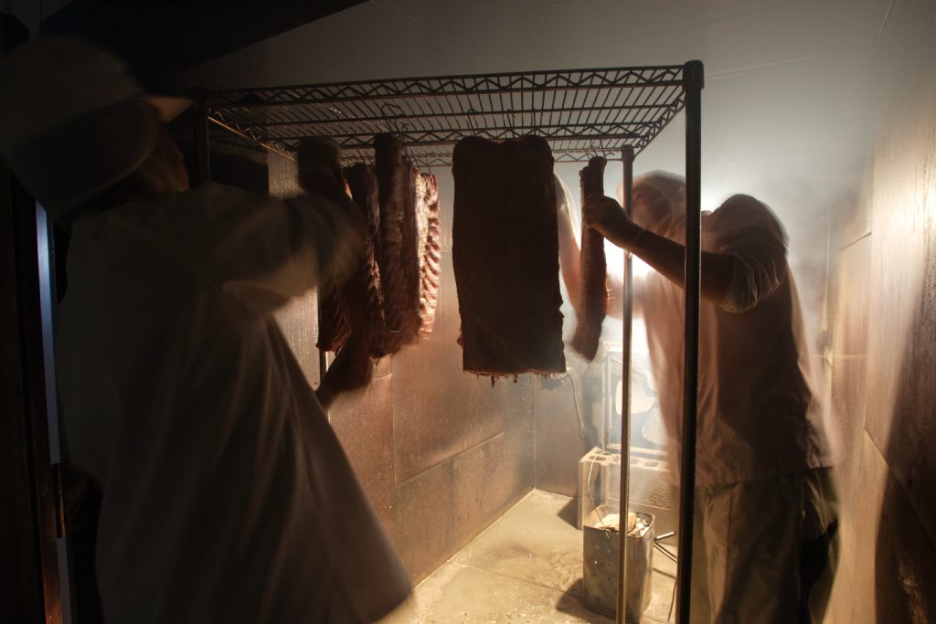 職人がベーコンの出来上がりを確認している