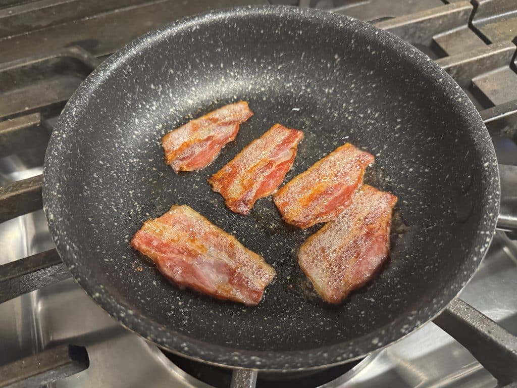 フライパンで弱火にかけたベーコン